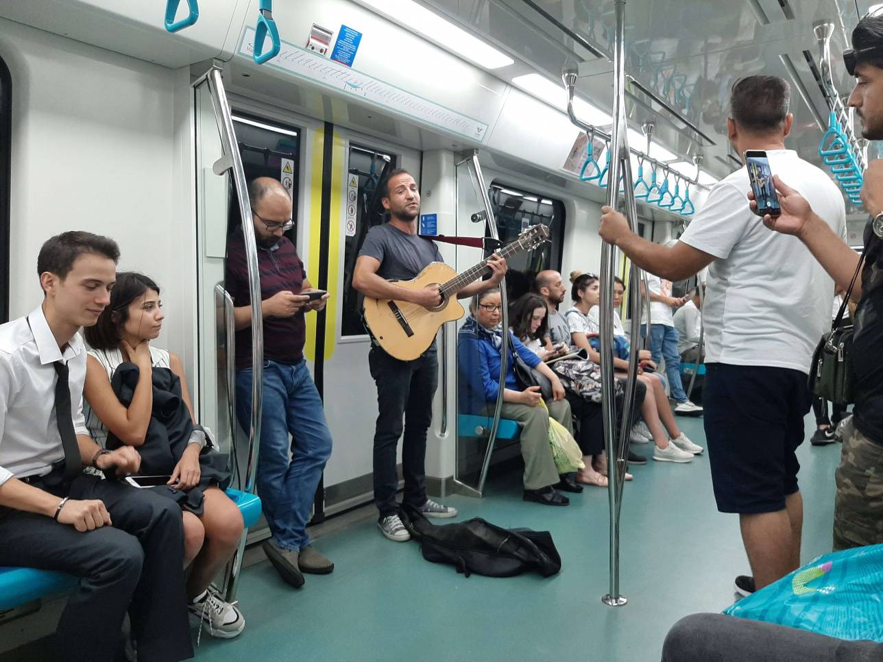 Метро ішінде ән тыңдап отырған жолаушылар 