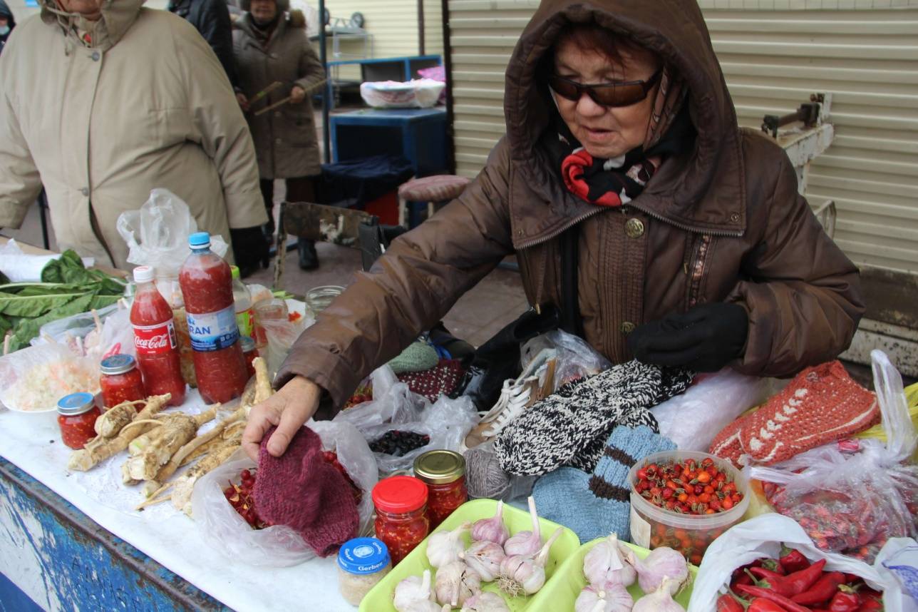 Өздайындағын тосаппен бірге балалардың қолғабын сатып отырған әже 